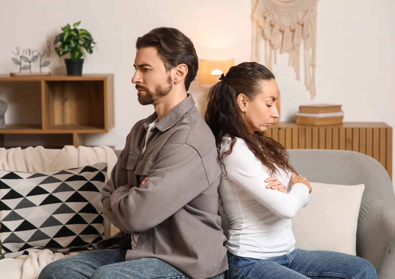 Couple sitting back to back on a couch, arms crossed